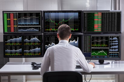 trader with 6 huge computer monitors watching many stocks to find trade entries and scalp the market