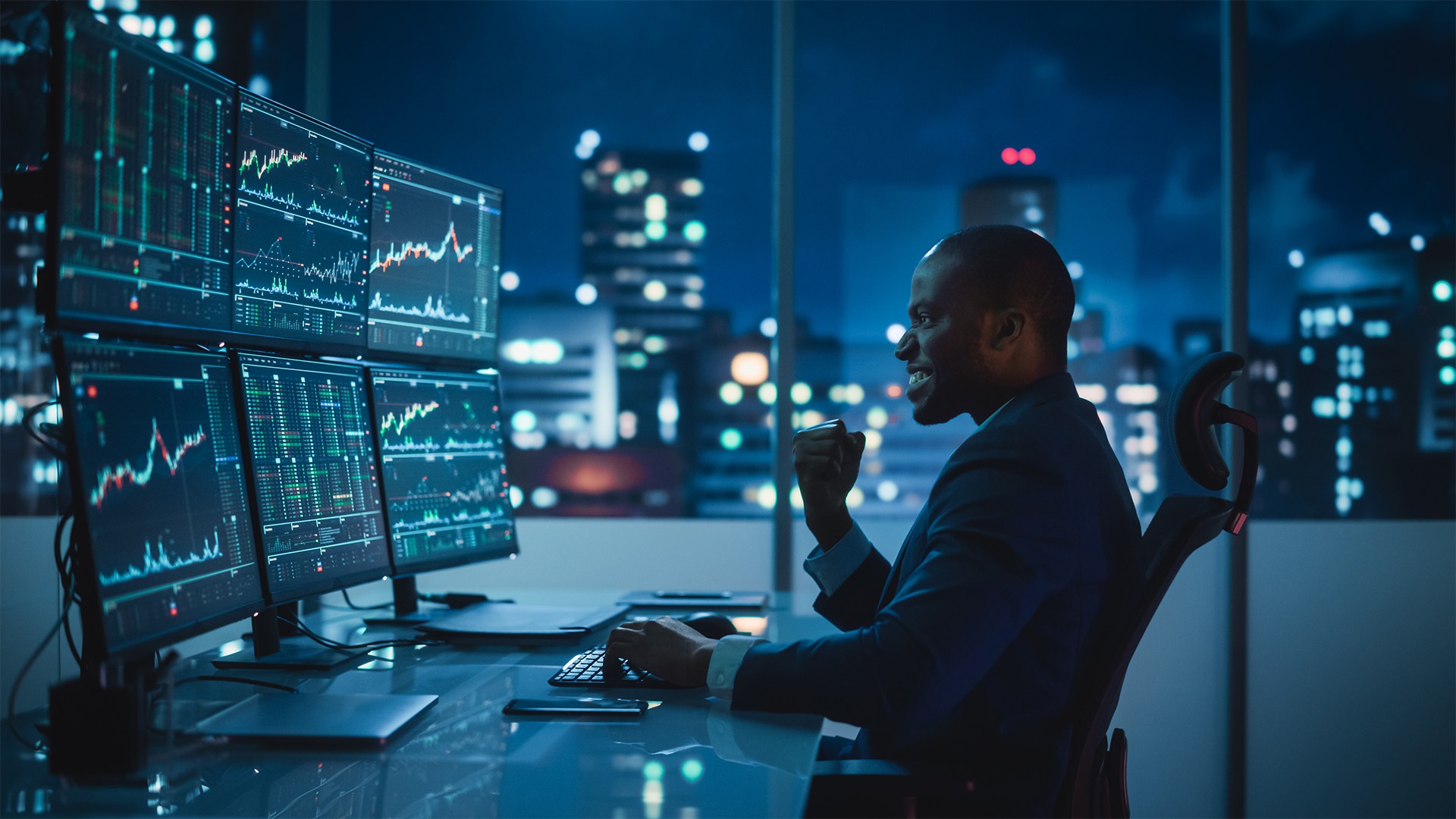types of forex traders position man of color in a business suit looking at stock charts on multiple computer monitors