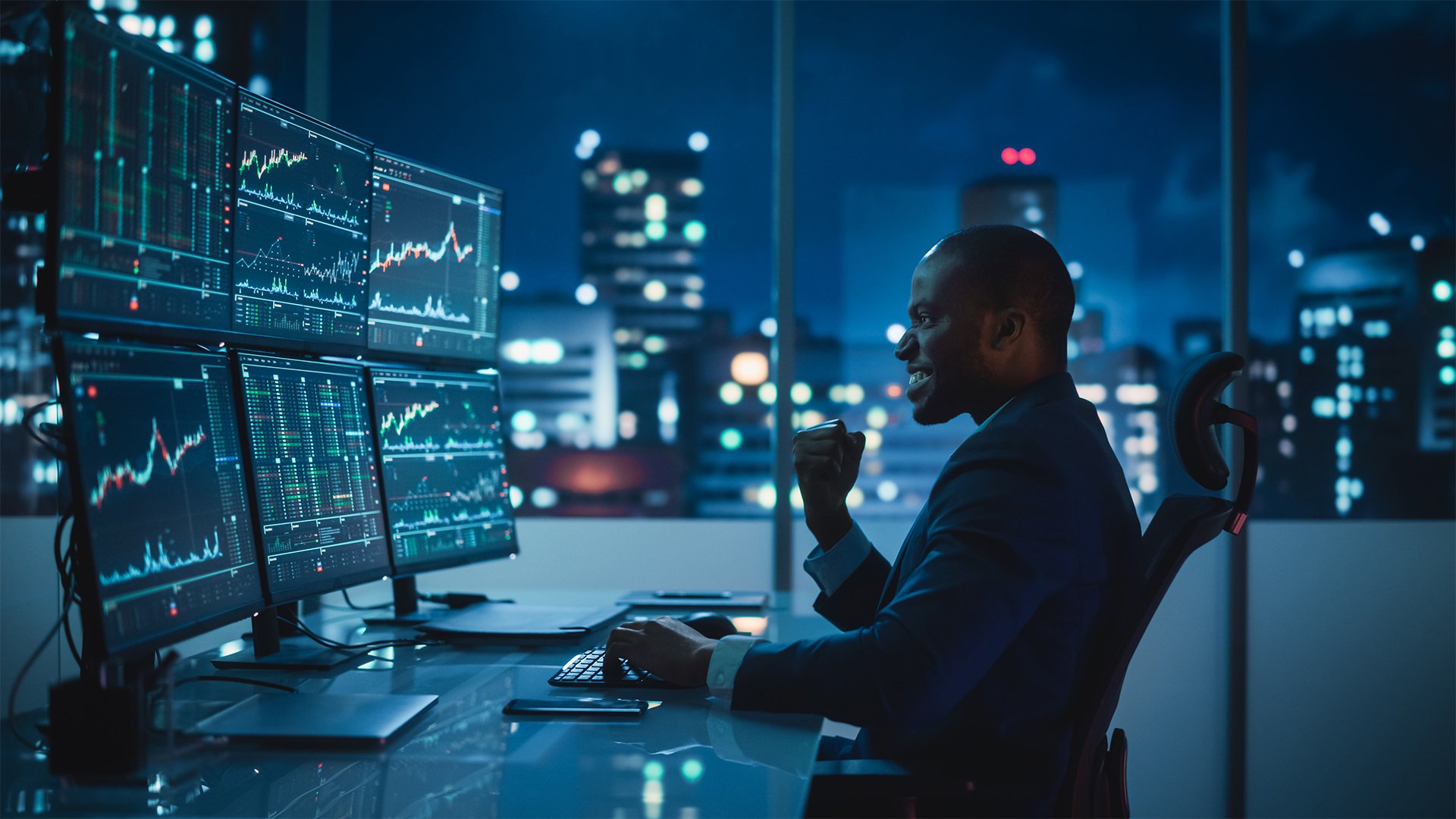 types of forex traders position man of color in a business suit looking at stock charts on multiple computer monitors